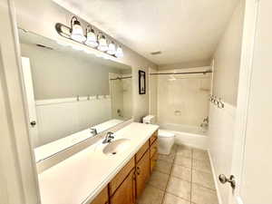 Bathroom featuring a single vanity with a laminate countertop, wood-finish cabinetry, a built-in bathtub with shower, beadboard wainscoting, and tile flooring