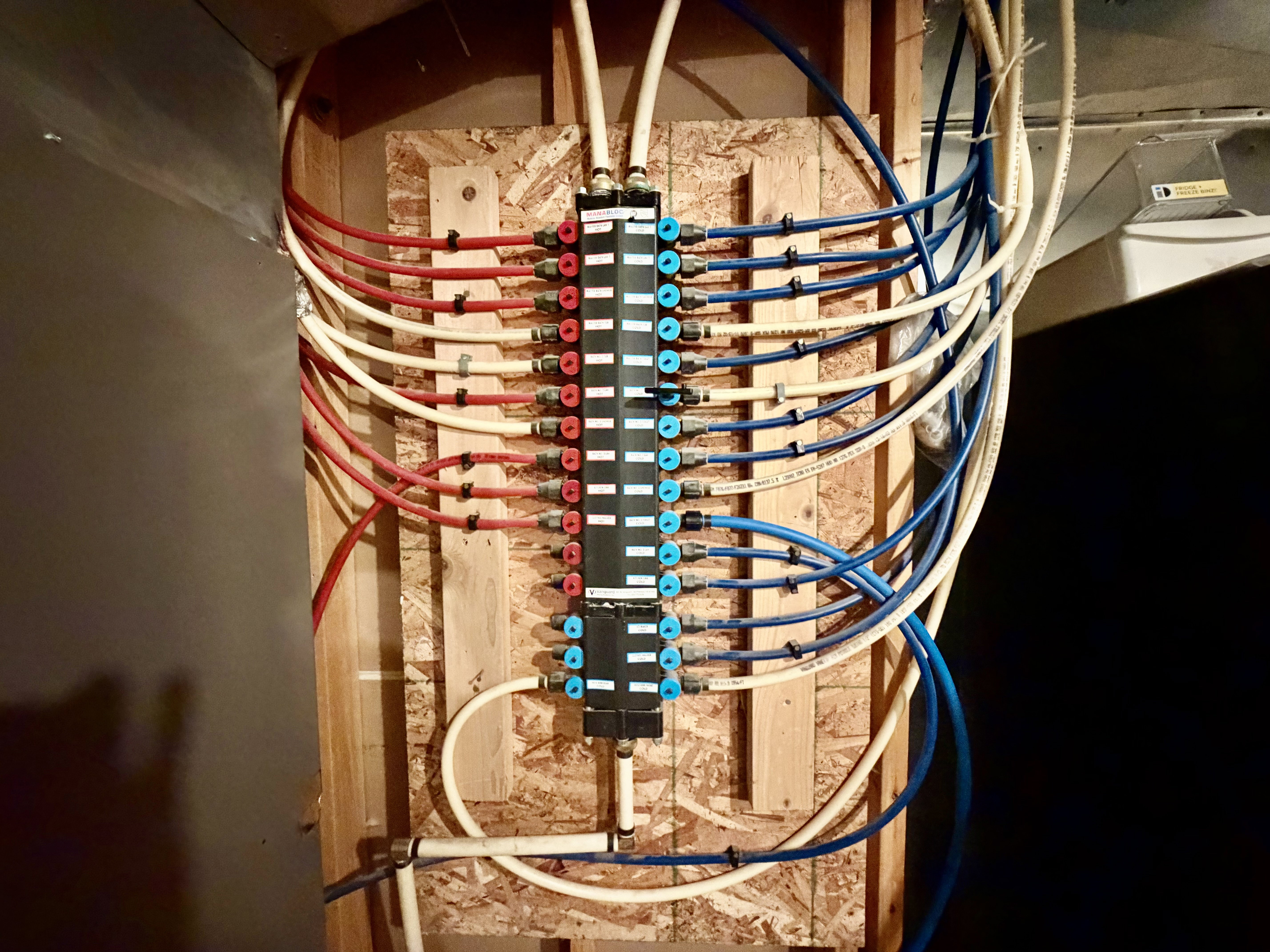 Centralized PEX plumbing manifold system mounted on a wood-sheathed wall