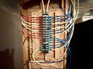 Centralized PEX plumbing manifold system mounted on a wood-sheathed wall