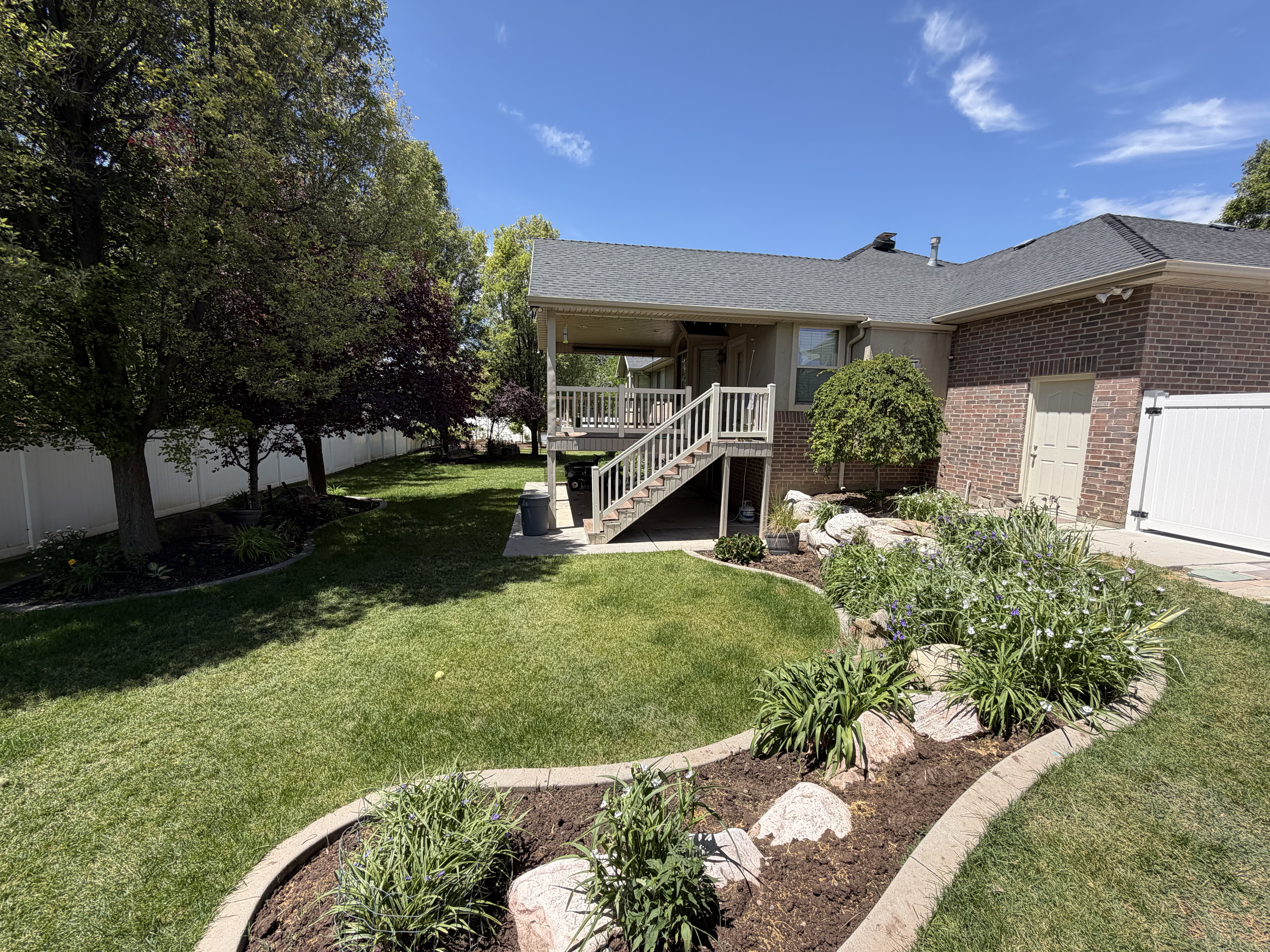 Expansive backyard featuring a multi-level deck, mature trees, and a decorative rock garden