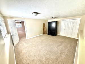 Carpeted room featuring a white paneled door, a window with horizontal blinds, and bi-fold closet doors