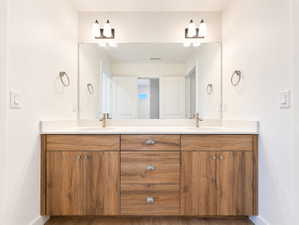 Double vanity featuring wood-finish cabinetry, white countertops, dual undermount sinks, and brushed nickel hardware