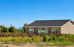 Newly constructed property featuring a dark shingle roof and light brown siding