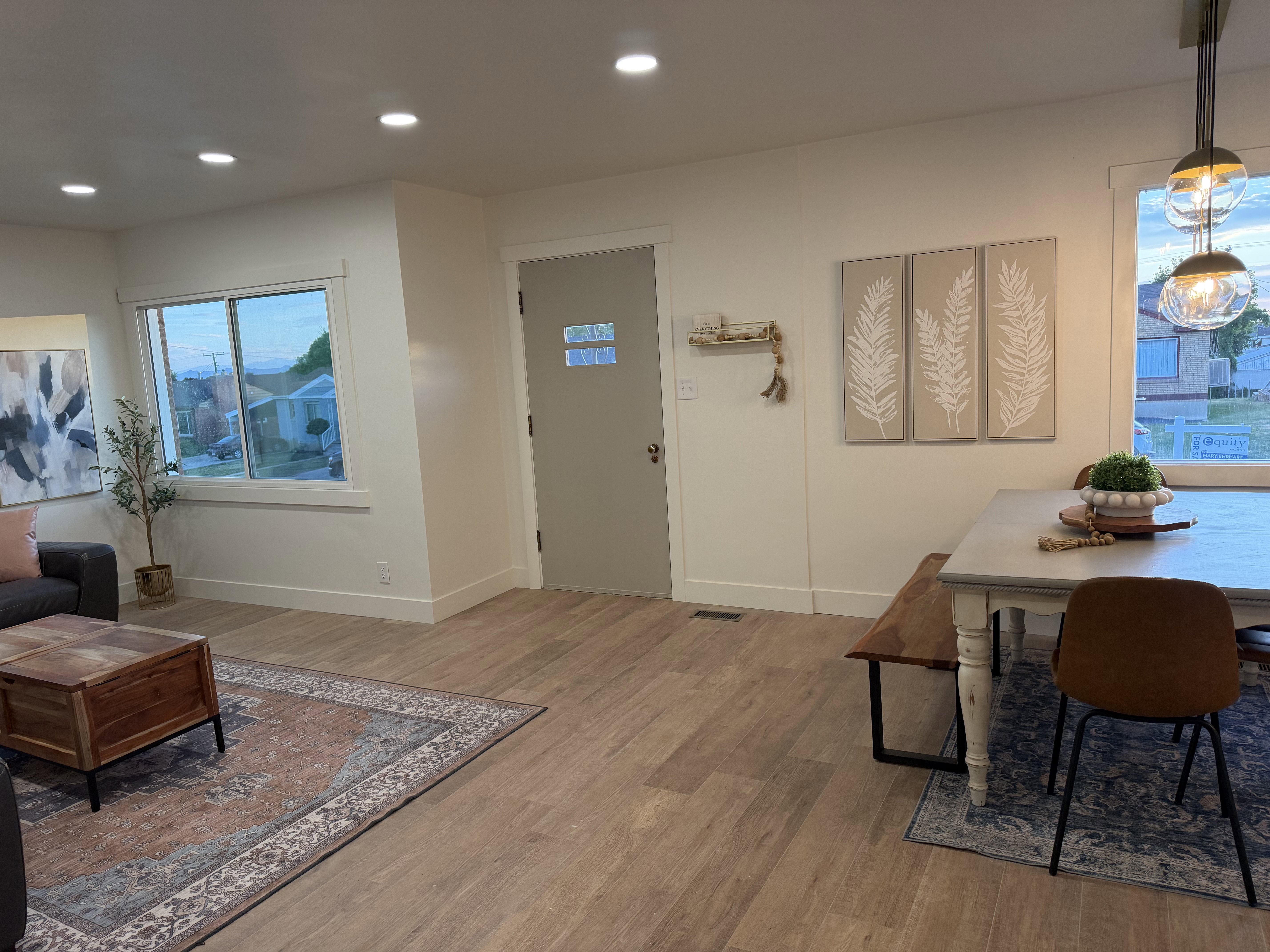 Open-concept living space featuring wood-finish flooring, recessed lighting, and a front entry door with privacy glass