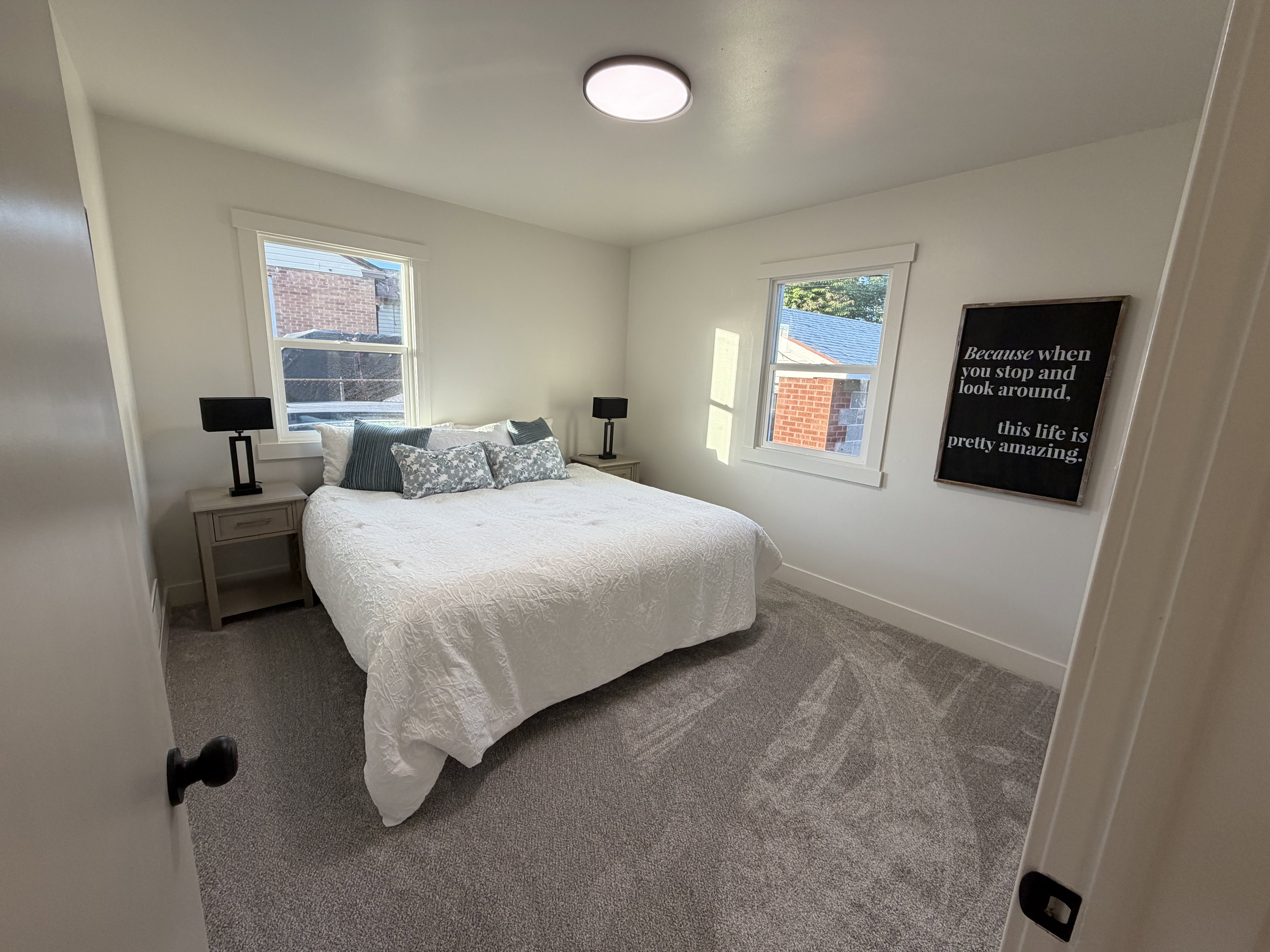 Room featuring two windows, neutral wall tones, and gray carpeting