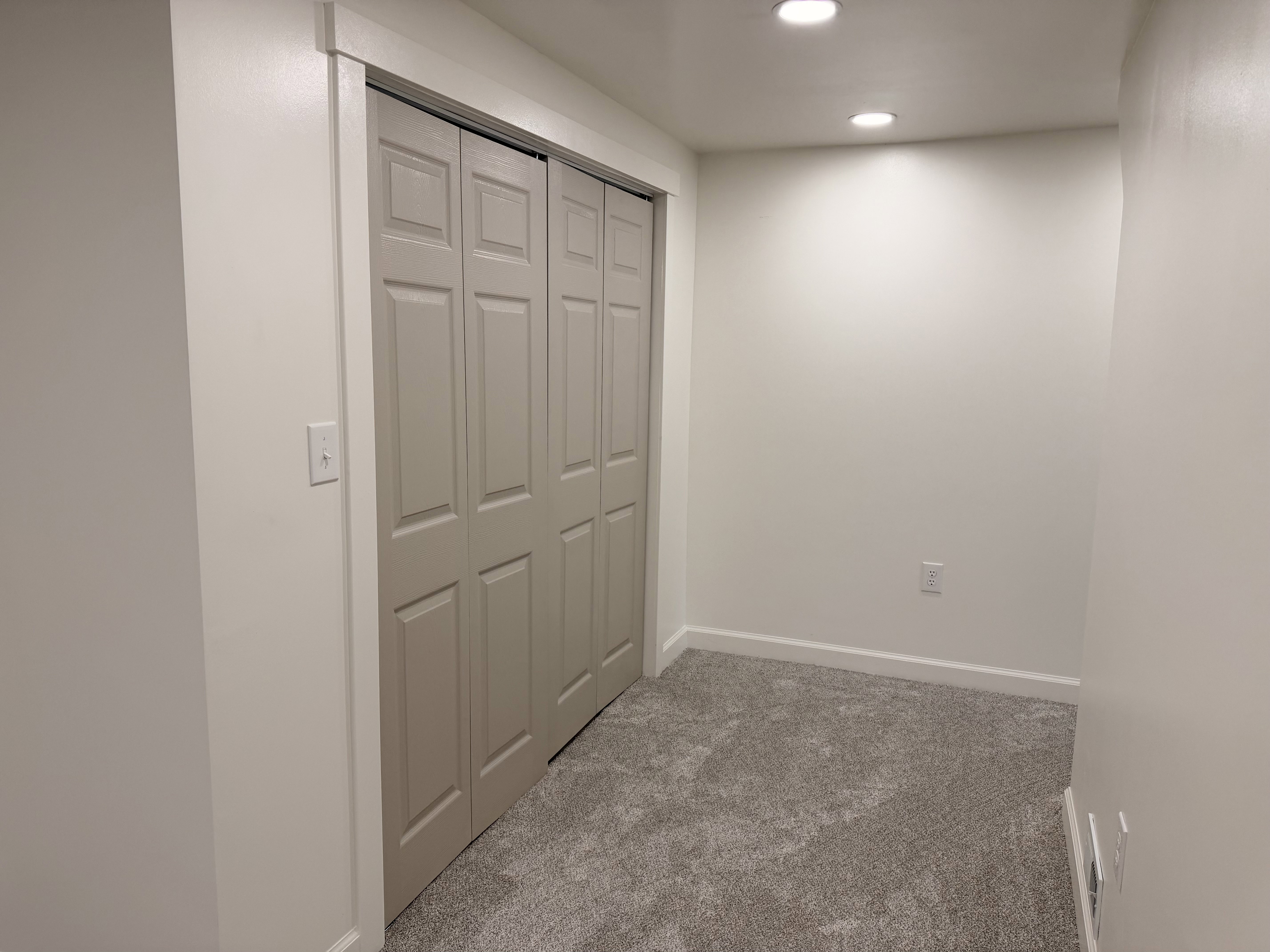 Built-in bi-fold closet doors, recessed lighting, neutral wall paint, white trim, and gray carpet