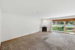 Living area featuring a kiva fireplace, broad sliding glass doors, white walls, and neutral carpeting