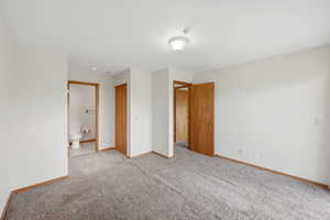 Spacious room featuring neutral carpeting, light-toned walls, wood-finish trim, and multiple doorways