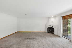 Spacious living area featuring a corner kiva-style fireplace with a black insert, an overhead recessed light, and a sliding glass door