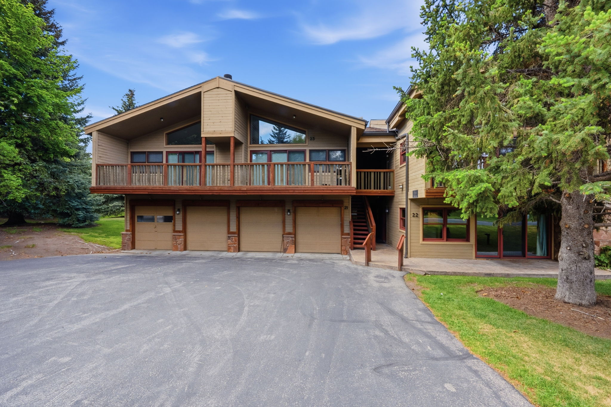 Contemporary multi-level residence featuring a sloped roofline, wood-finish siding, and a large elevated deck with wood railing