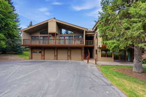 Contemporary multi-level residence featuring a sloped roofline, wood-finish siding, and a large elevated deck with wood railing