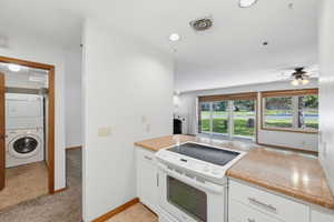 Kitchen featuring white cabinetry, light-colored countertops, and a white electric range