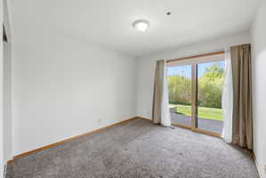 Carpeted room featuring a ceiling-mounted light fixture, white walls, and wood-finish baseboards