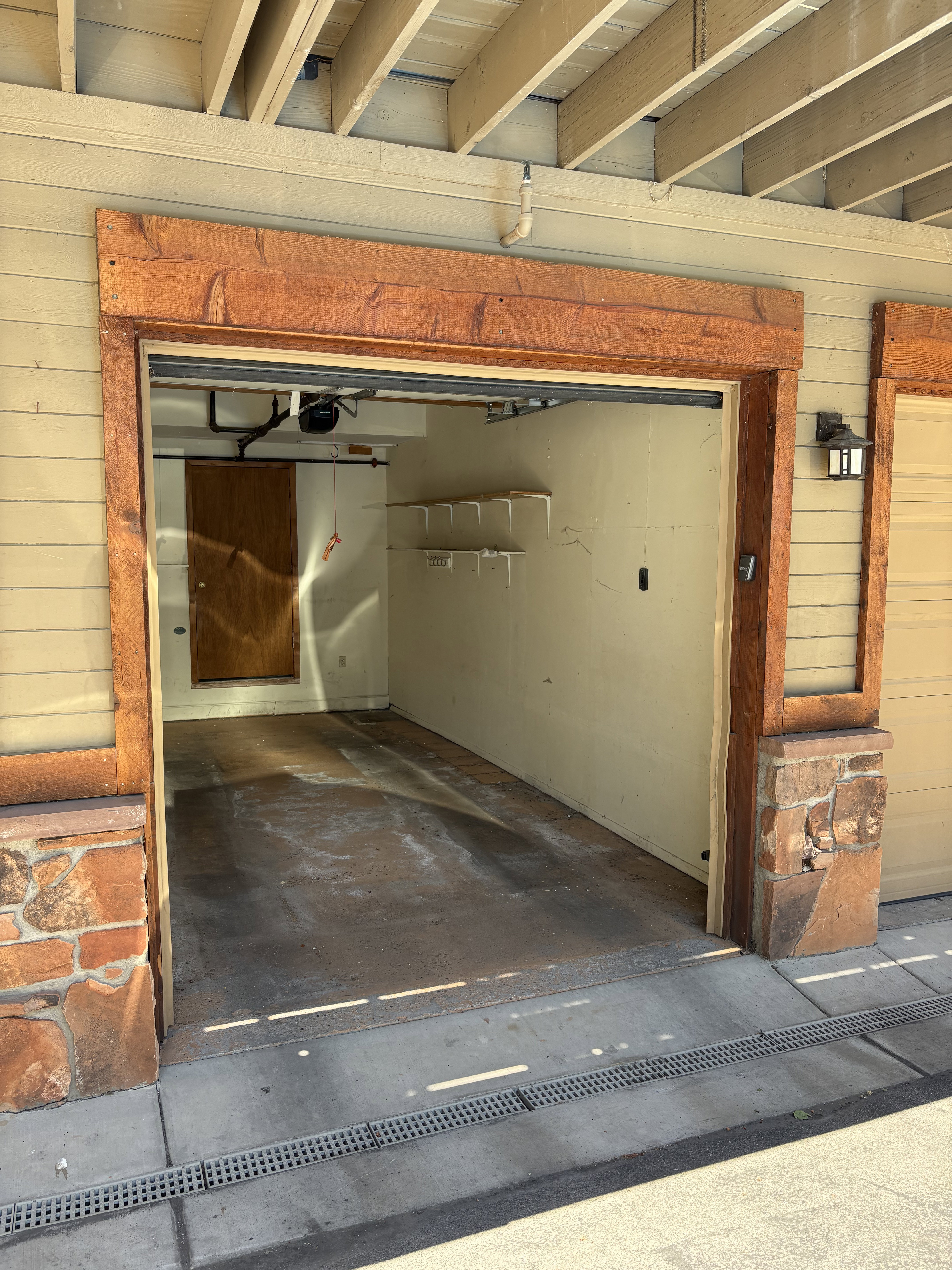 Attached garage with a wood-finish header and stone veneer pillars