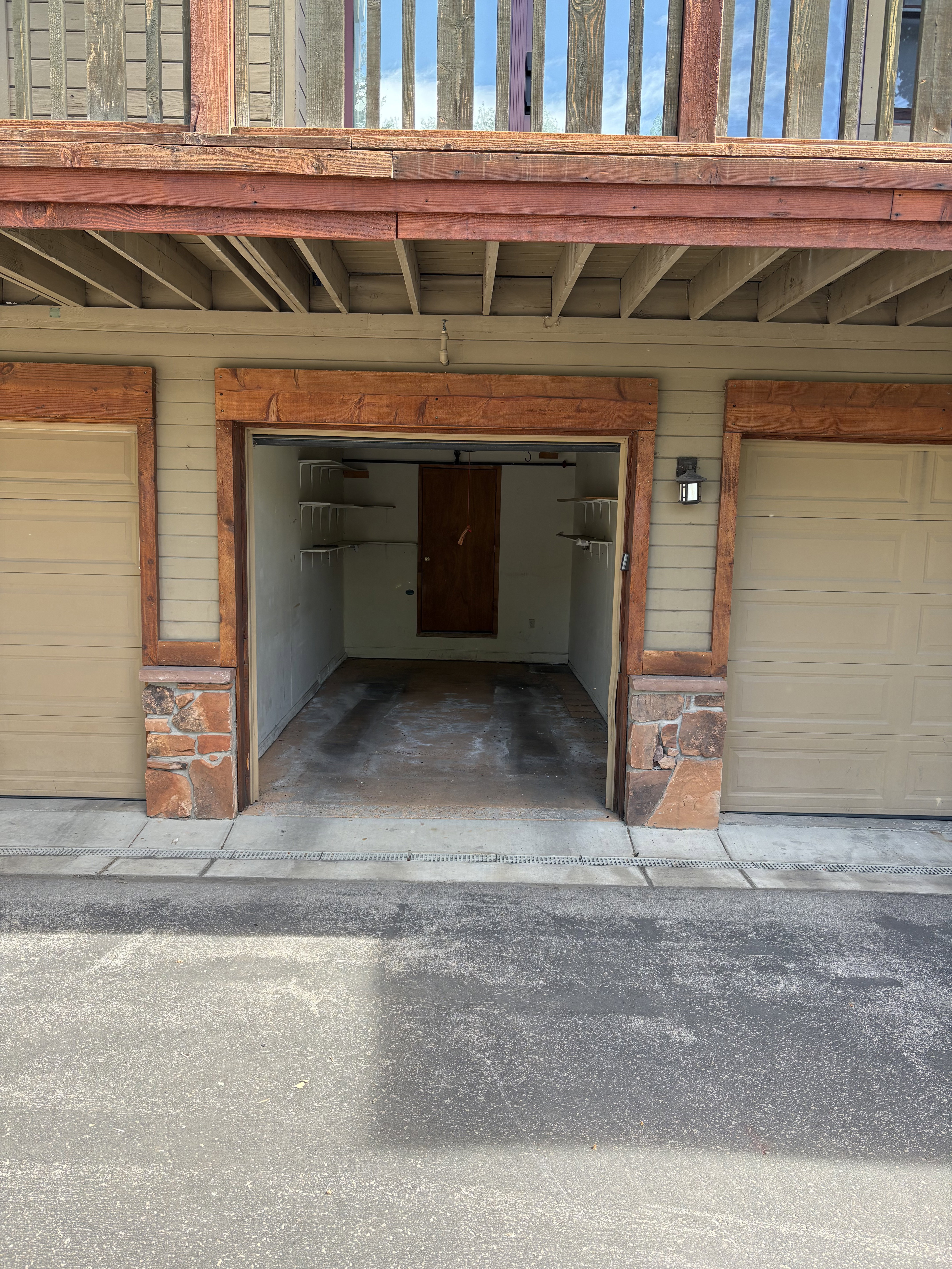 Garage space featuring a roll-up door, built-in shelving, a wood-paneled door, and an exterior wall light fixture