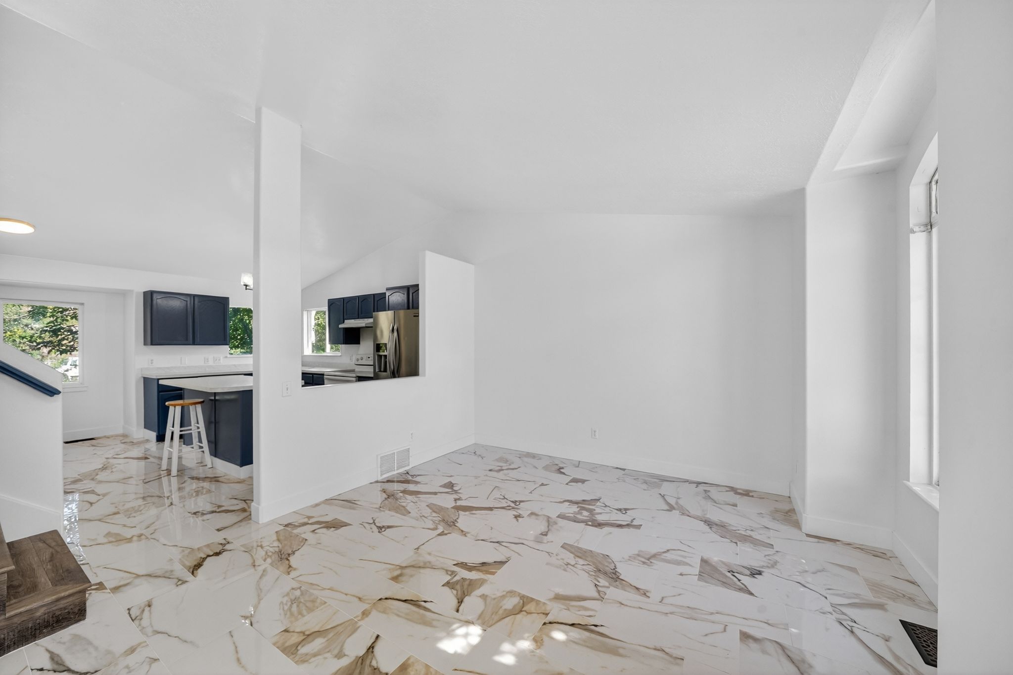 Spacious room featuring white walls and marble-patterned flooring