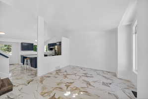 Spacious room featuring white walls and marble-patterned flooring