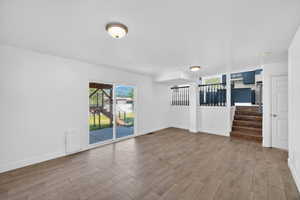 Spacious lower-level area featuring wood-finish tile flooring, recessed lighting, and a sliding glass door