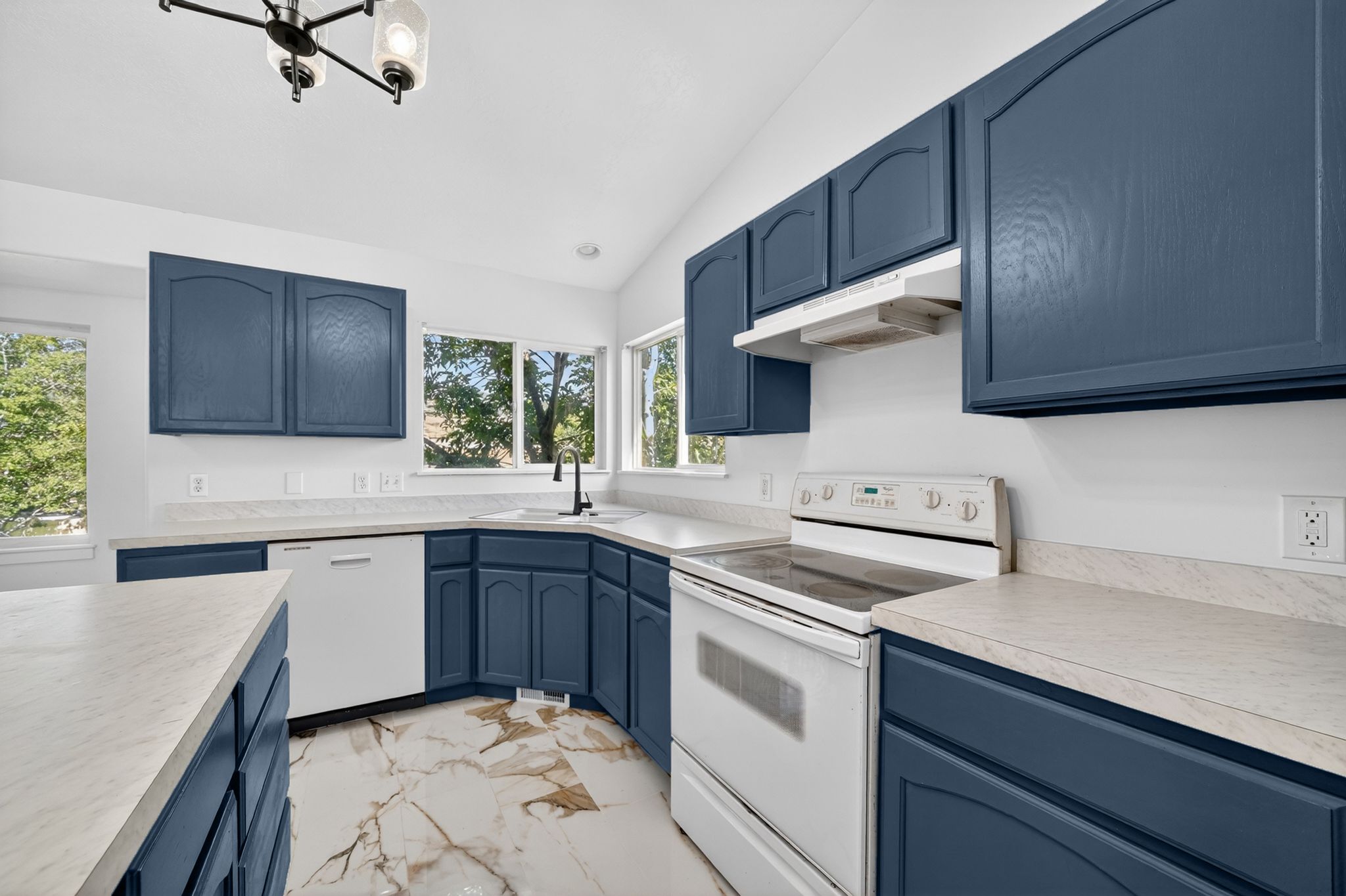 Kitchen featuring blue cabinetry, light countertops, integrated dishwasher, and a built-in range