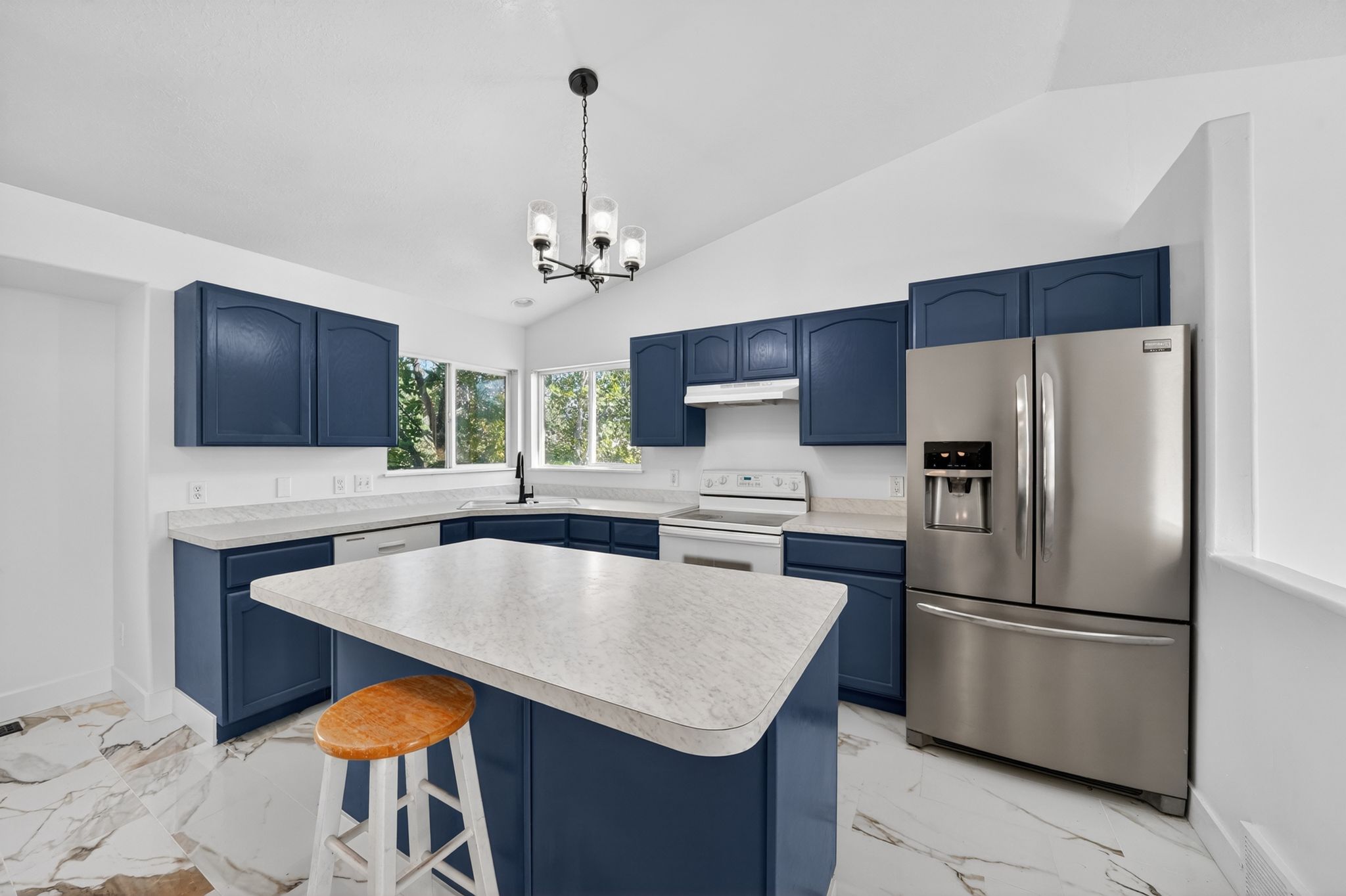 Kitchen featuring navy cabinetry, light-toned countertops, a stainless steel French door refrigerator, white range and dishwasher, and a central island