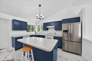 Kitchen featuring navy cabinetry, light-toned countertops, a stainless steel French door refrigerator, white range and dishwasher, and a central island