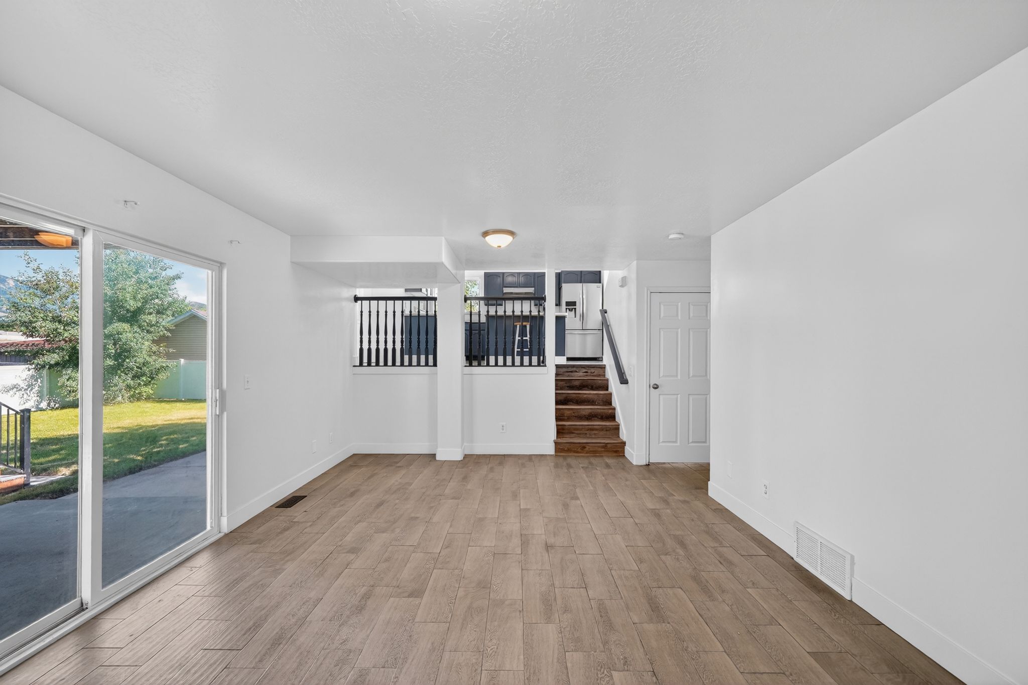 Spacious living area featuring wood-finish flooring, white walls, and a recessed ceiling light