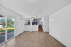 Spacious living area featuring wood-finish flooring, white walls, and a recessed ceiling light