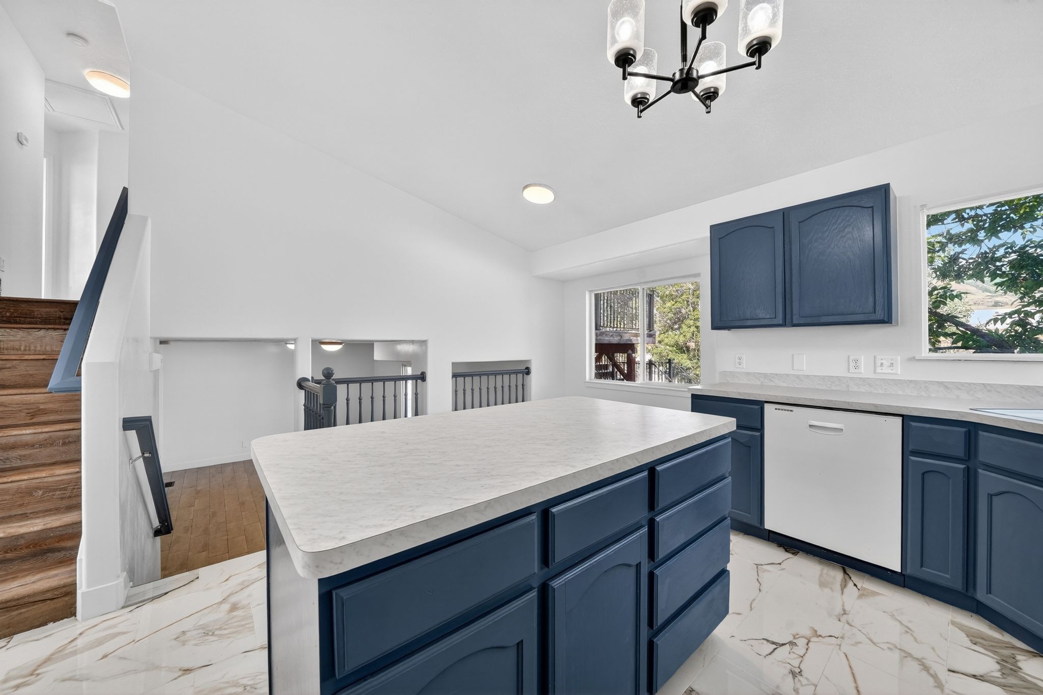Kitchen featuring a central island with countertop, navy cabinetry, a built-in dishwasher, and a contemporary chandelier