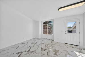 Spacious room featuring large format marble-look tile flooring, white walls, and a contemporary ceiling light fixture