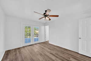 Wood-finish flooring throughout, white baseboards, and a ceiling fan with integrated lighting