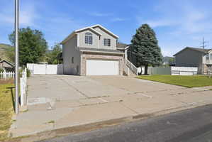 Two-story residence featuring light gray siding, a prominent two-car garage with a white door, and a partial brick facade