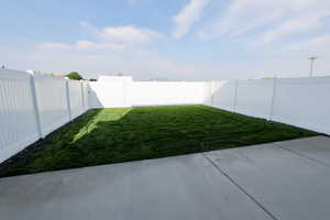 Expansive backyard featuring a new lawn, concrete patio, and full vinyl privacy fencing