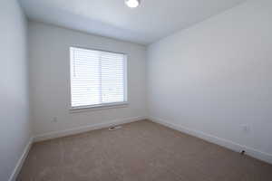 Room with light tan carpeting, white baseboards, and a single window featuring horizontal blinds