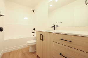 Bathroom featuring a light wood-finish vanity with matte black hardware, a light-toned countertop, and a large wall-mounted mirror