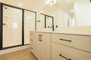 Modern vanity with light wood-finish cabinetry, matte black hardware, and a solid surface countertop