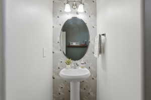 Pedestal sink with a wall-mounted faucet and an oval mirror