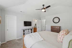 Vaulted ceiling with a ceiling fan, carpeted flooring, and a white panel door