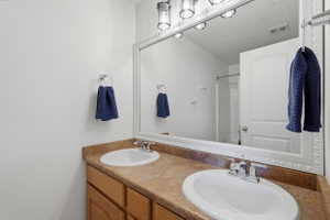 Dual vanity featuring laminate countertops, two undermount sinks with chrome fixtures, and wood-finish cabinetry