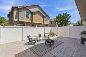 Patio area featuring stamped concrete flooring, white privacy fencing, and a built-in planter box