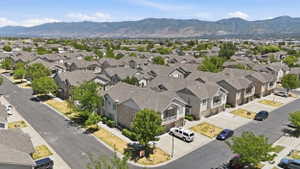 Aerial perspective showcasing multiple properties featuring light-colored siding, dark shingle roofs, integrated garages, and street-facing entrances