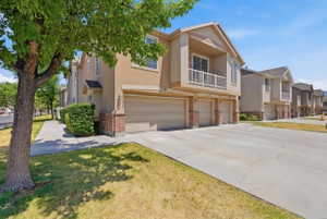 Stucco exterior with brick detailing, multiple attached garages, and a private balcony featuring a white railing