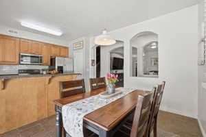 Dining area featuring a wood-finish table, a white pendant light fixture, and tile flooring