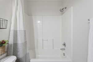 White tile shower and tub combination featuring chrome fixtures and a fixed showerhead