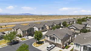 Residential streetscape featuring a curved asphalt road, mature trees, and a series of two-story homes with attached garages