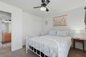 Bedroom featuring a ceiling fan with integrated lighting, carpet flooring, and a double-door closet