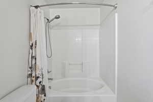 White tub and shower combination with a tiled surround and a built-in soap dish