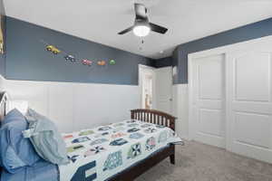 Bedroom featuring a vaulted ceiling with a ceiling fan, board and batten wall paneling, and sliding closet doors