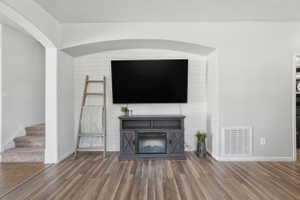 Living area featuring wood-finish flooring and a built-in entertainment niche with shiplap-style accent wall