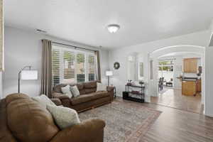 Living area featuring wood-finish flooring, white walls, and recessed lighting