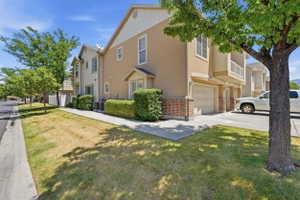 Two-story townhome featuring a neutral stucco exterior with brick accents and a two-car garage